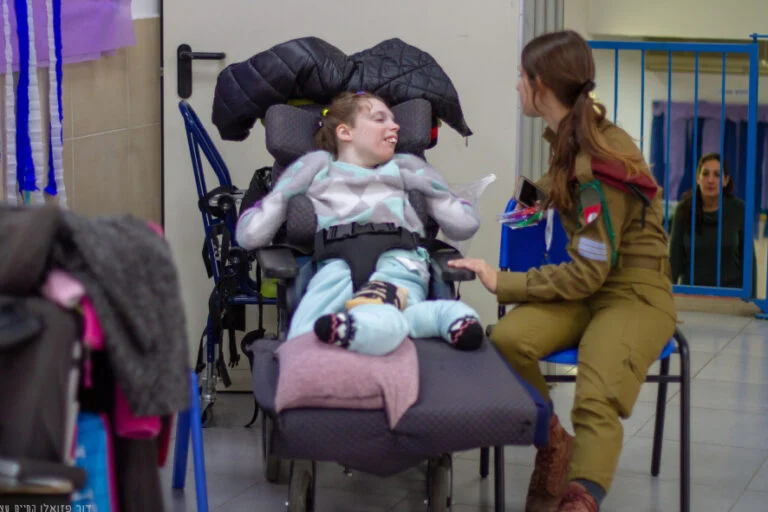 חיילת מתנדבת לצד נערה בכיסא גלגלים