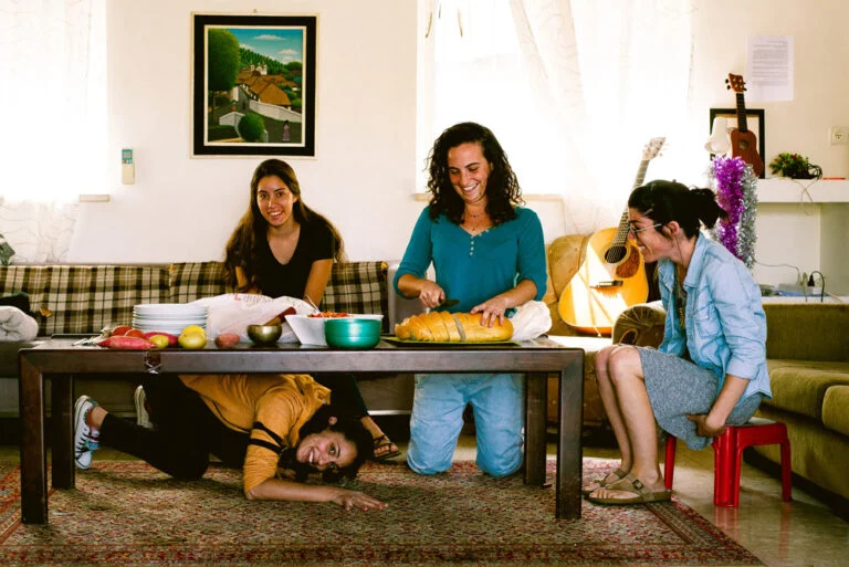 שלוש צעירות מכינות אוכל יחד בסלון