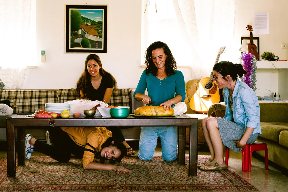 Three young women cooking together in a living room